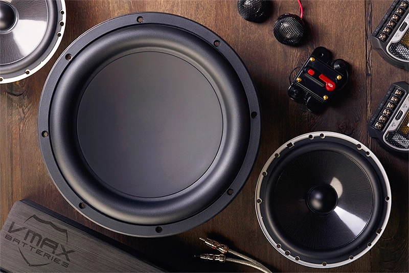 Vmax CT series AGM car audio battery alongside a high-performance subwoofer, speakers, and crossover system.