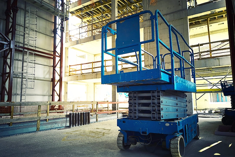 Industrial scissor lift powered by heavy-duty VMAX deep cycle AGM batteries on an active construction site.