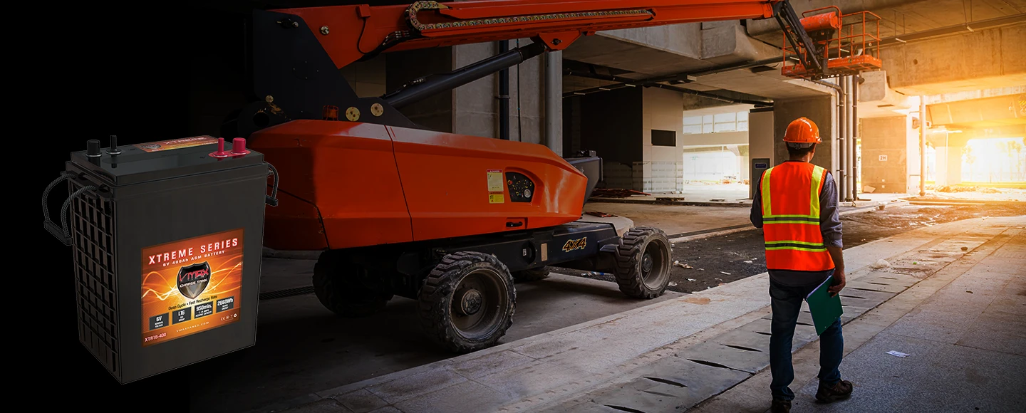 Industrial scissor lift powered by heavy-duty VMAX deep cycle AGM batteries on an active construction site.
