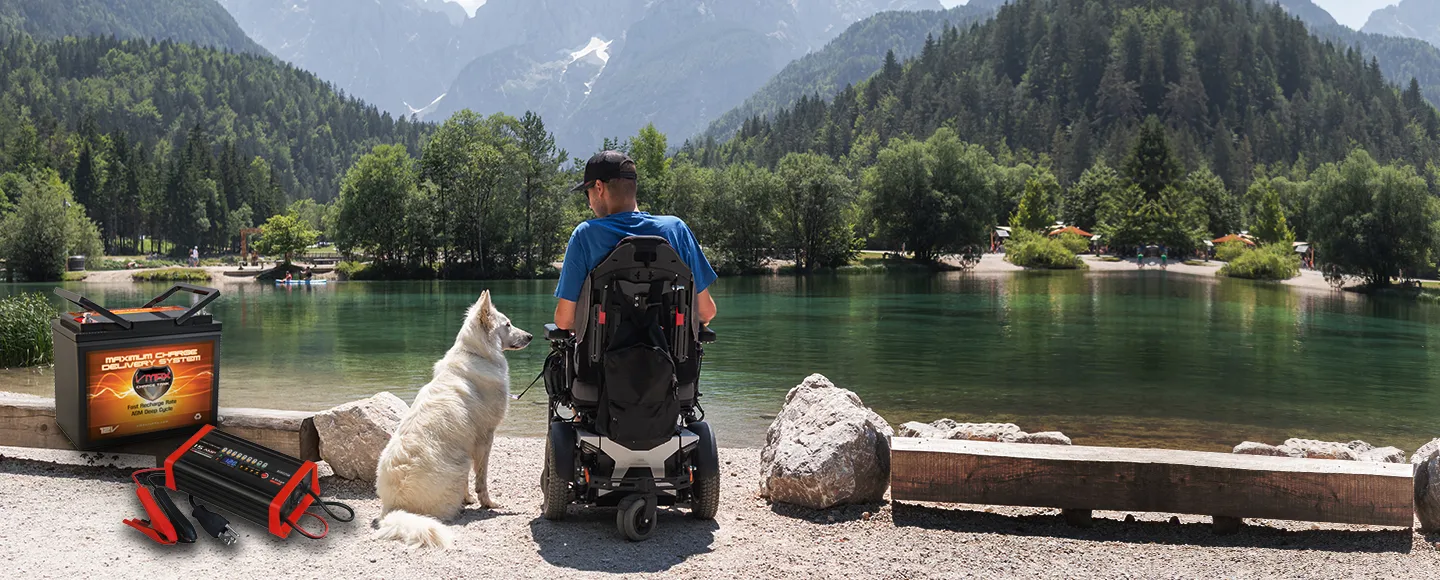 Vmax deep cycle AGM mobility battery and 15A smart charger powering an electric wheelchair by a mountain lake.